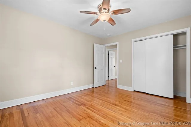 an empty room with wooden floor and ceiling fan