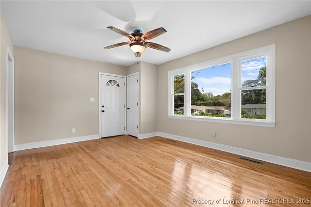 a view of an empty room with a window and wooden floor