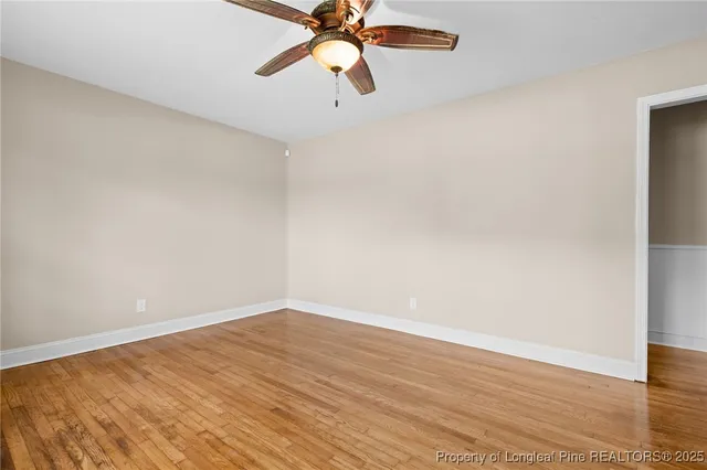 a view of a room with wooden floor ceiling fan and window