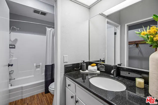 a bathroom with a granite countertop sink and a mirror with bathtub