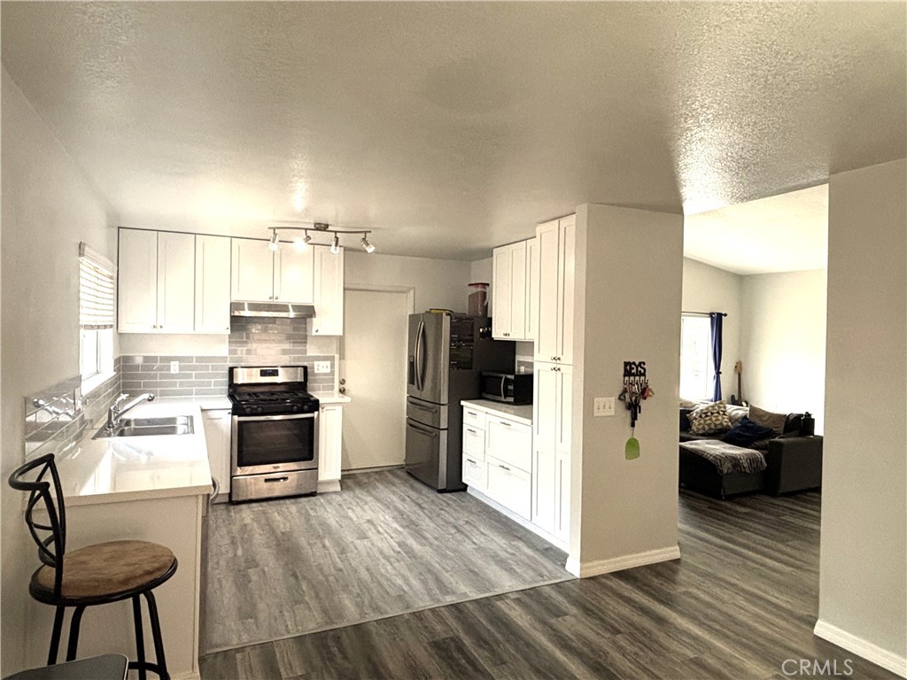 6845 Butte Drive Riverside, CA 92505 - Photo 7 of 27 a kitchen with stainless steel appliances a refrigerator a stove a sink dishwasher and wooden cabinets with wooden floor