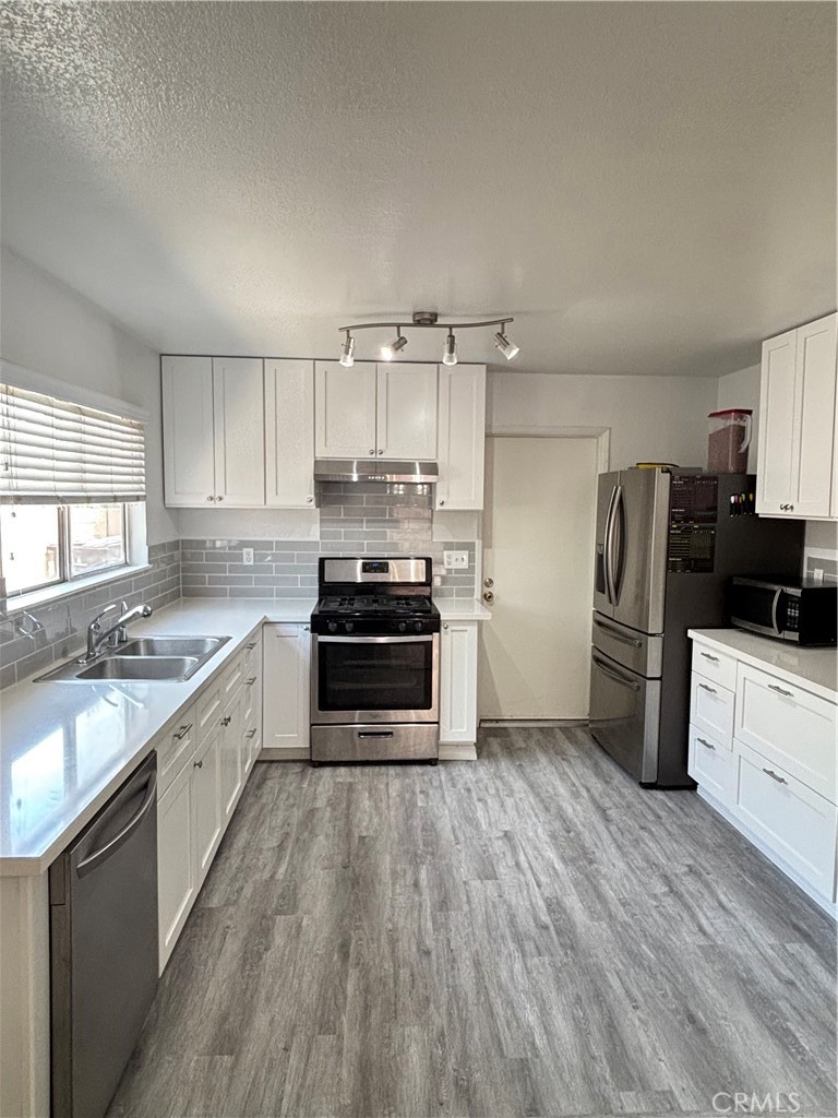 6845 Butte Drive Riverside, CA 92505 - Photo 10 of 27 a kitchen with granite countertop a refrigerator oven a sink dishwasher and wooden floor