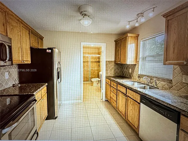 a kitchen with stainless steel appliances granite countertop a refrigerator and a sink