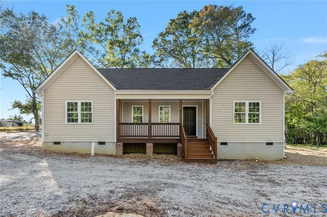front view of house with a yard and large trees