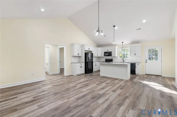 an empty room with wooden floor and kitchen view