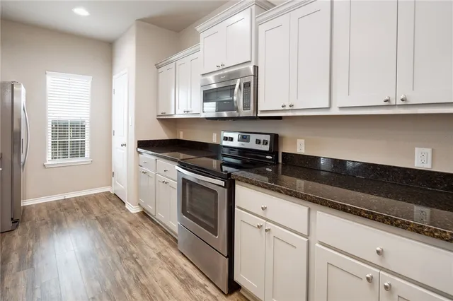 a white kitchen with granite countertop stainless steel appliances