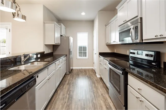 a kitchen with granite countertop a sink dishwasher stove and oven