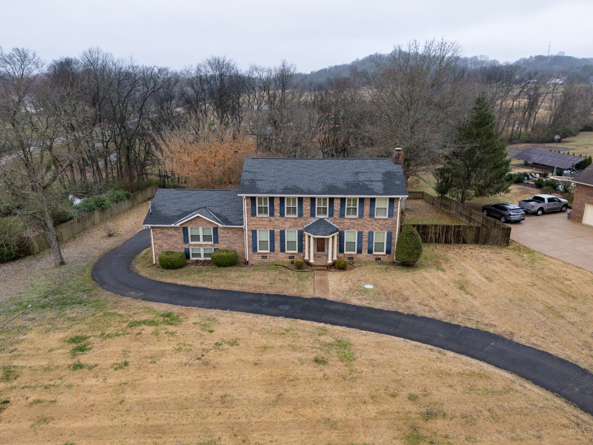 an aerial view of a house with yard and trees in the background