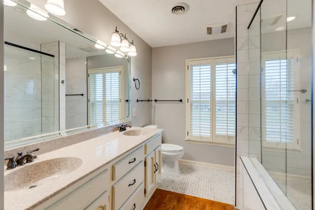 a bathroom with a granite countertop sink a large mirror a shower and a bathtub