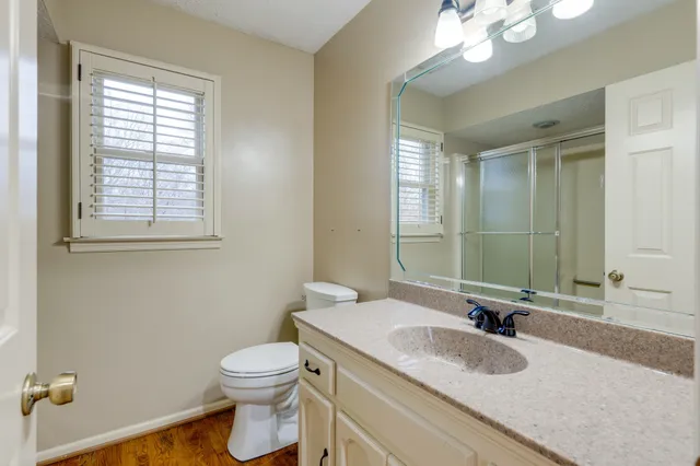 a bathroom with a granite countertop sink a toilet and a mirror