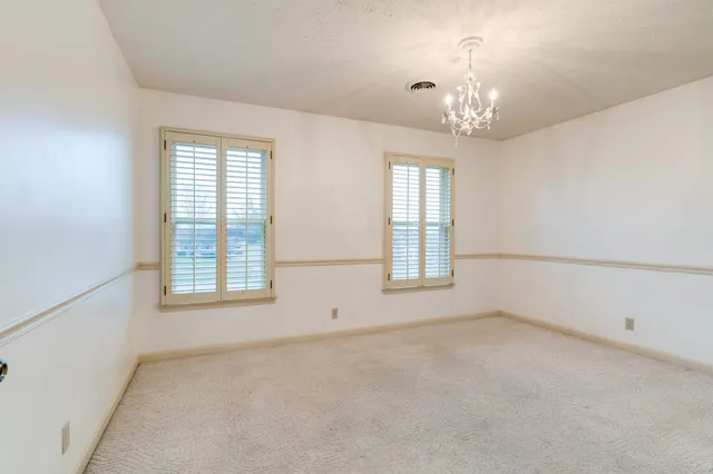 en empty room with windows and chandelier