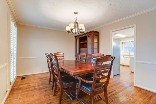 a view of a dining room with furniture a chandelier and wooden floor