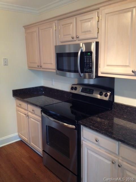 1301 Queens Road, Unit 506 Charlotte, NC 28207 - Photo 7 of 8 a kitchen with granite countertop white cabinets and black appliances