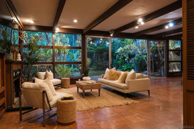 a living room with patio furniture and a garden