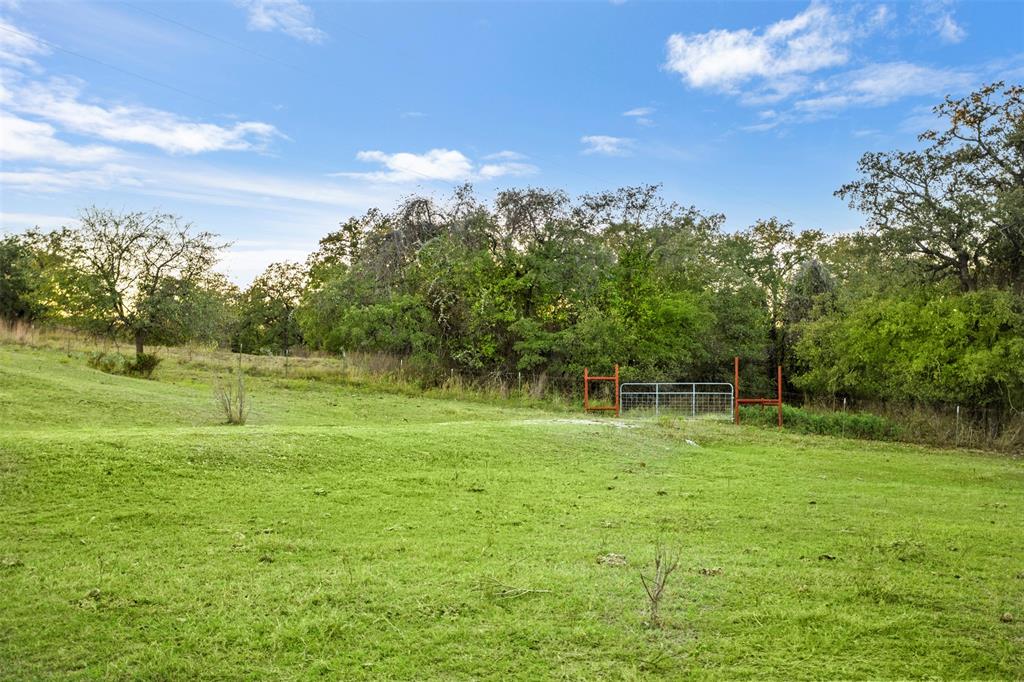 199 Cheyenne Trail Springtown, TX 76082 - Photo 7 of 22 Expansive green space featuring a metal gate entrance, perimeter fencing, and mature trees defining the property lines