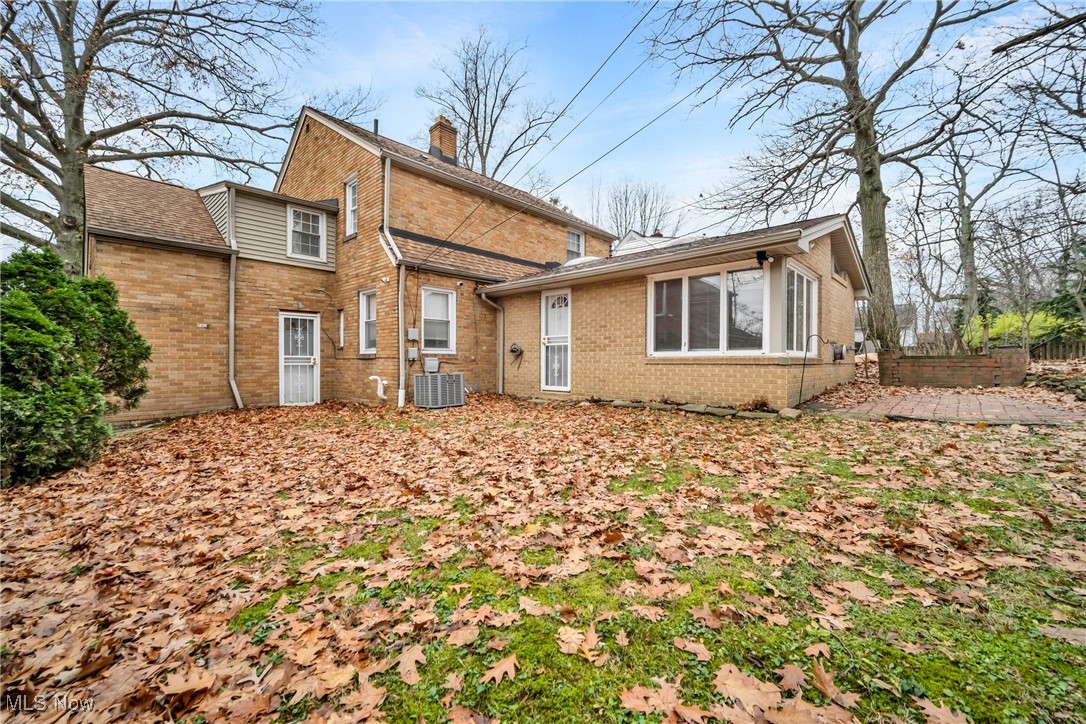 1605 Laclede Road Cleveland, OH 44121 - Photo 6 of 40 Rear view of house with central AC, brick siding, fence, and a chimney