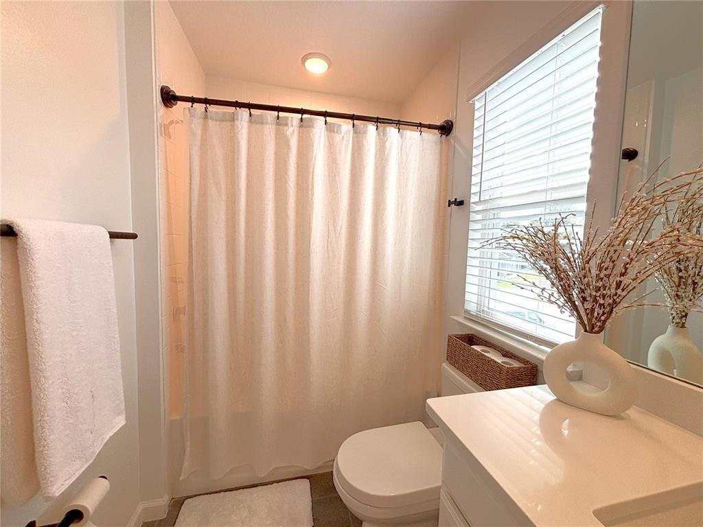 921 Spring Palms Loop Orlando, FL 32828 - Photo 21 of 30 a bathroom with a sink a toilet a mirror and shower curtain