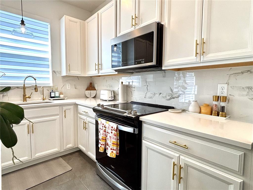 921 Spring Palms Loop Orlando, FL 32828 - Photo 8 of 30 a kitchen with stainless steel appliances granite countertop a sink a stove and microwave