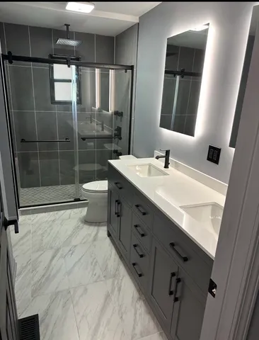 a bathroom with a double vanity sink toilet and shower