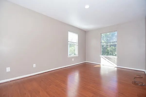 an empty room with wooden floor and windows
