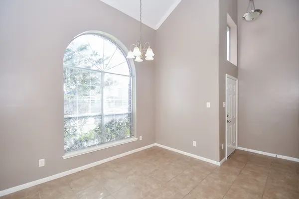 an empty room with a chandelier fan and windows