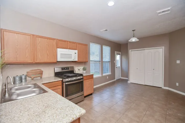 a kitchen with granite countertop a stove top oven sink and cabinets