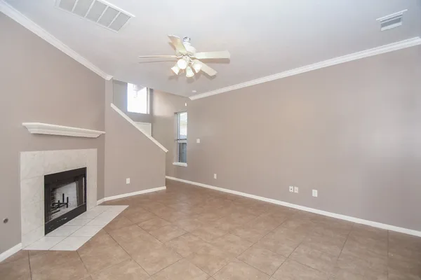 a view of an empty room with chandelier fan and fire place