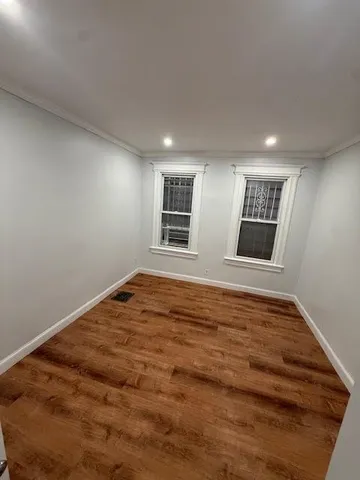 a view of an empty room with window and wooden floor