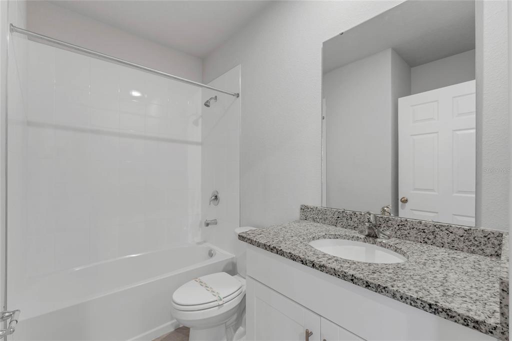 3472 Monaco Drive Davenport, FL 33897 - Photo 17 of 25 a bathroom with a granite countertop sink a toilet and shower