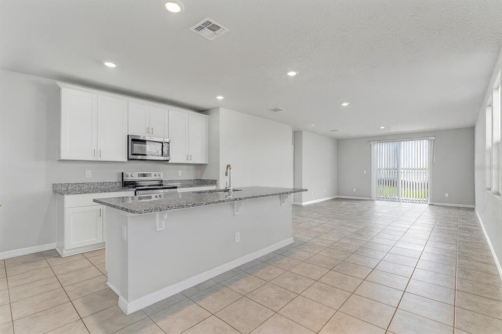 3472 Monaco Drive Davenport, FL 33897 - Photo 4 of 25 a large kitchen with stainless steel appliances granite countertop a sink and cabinets