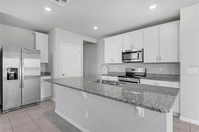 a kitchen with granite countertop a sink a microwave a stove and cabinets