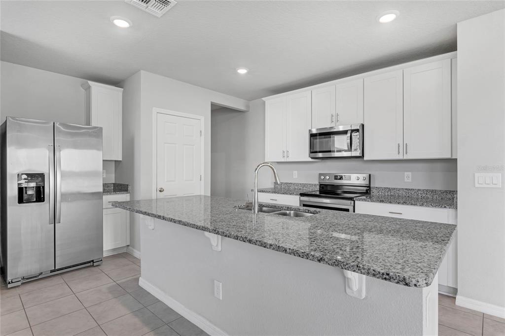 3472 Monaco Drive Davenport, FL 33897 - Photo 8 of 25 a kitchen with stainless steel appliances granite countertop a refrigerator a stove a sink and white cabinets