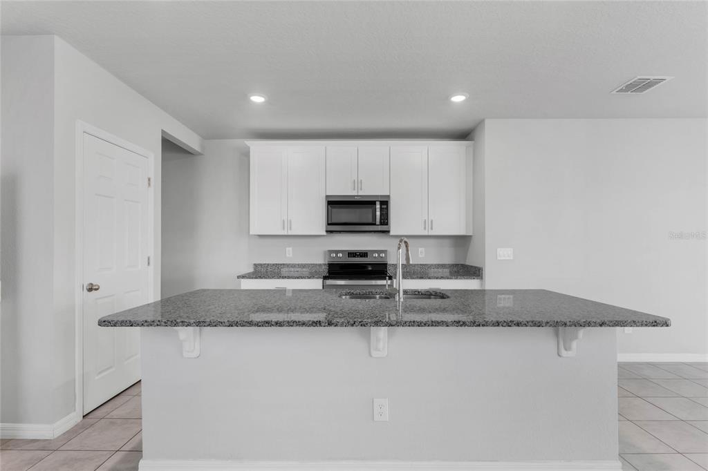 3472 Monaco Drive Davenport, FL 33897 - Photo 9 of 25 a kitchen with granite countertop a sink a microwave a stove and cabinets