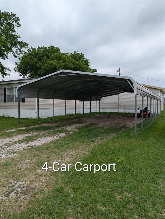 297 Lone Tree Lane Decatur, TX 76234 - Photo 19 of 26 The property includes an extensive carport with a metal roof, a gravel driveway, and a grassy area