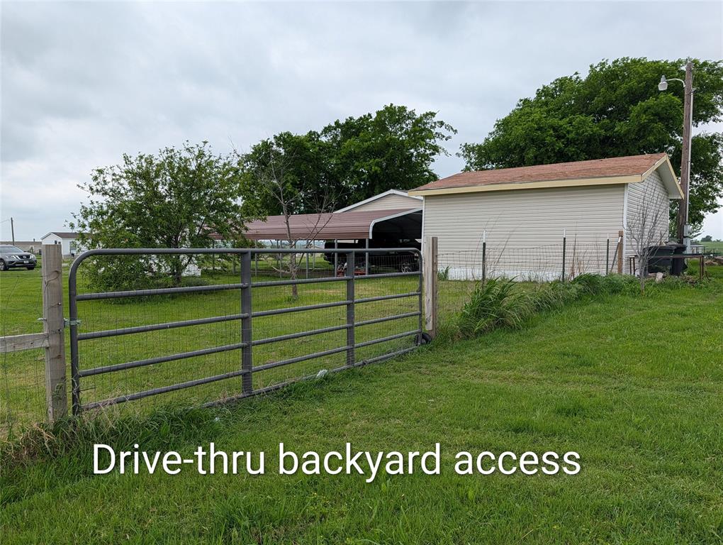 297 Lone Tree Lane Decatur, TX 76234 - Photo 20 of 26 The property features a metal gate providing access to the backyard, which includes a shed with light-colored siding and a brown roof