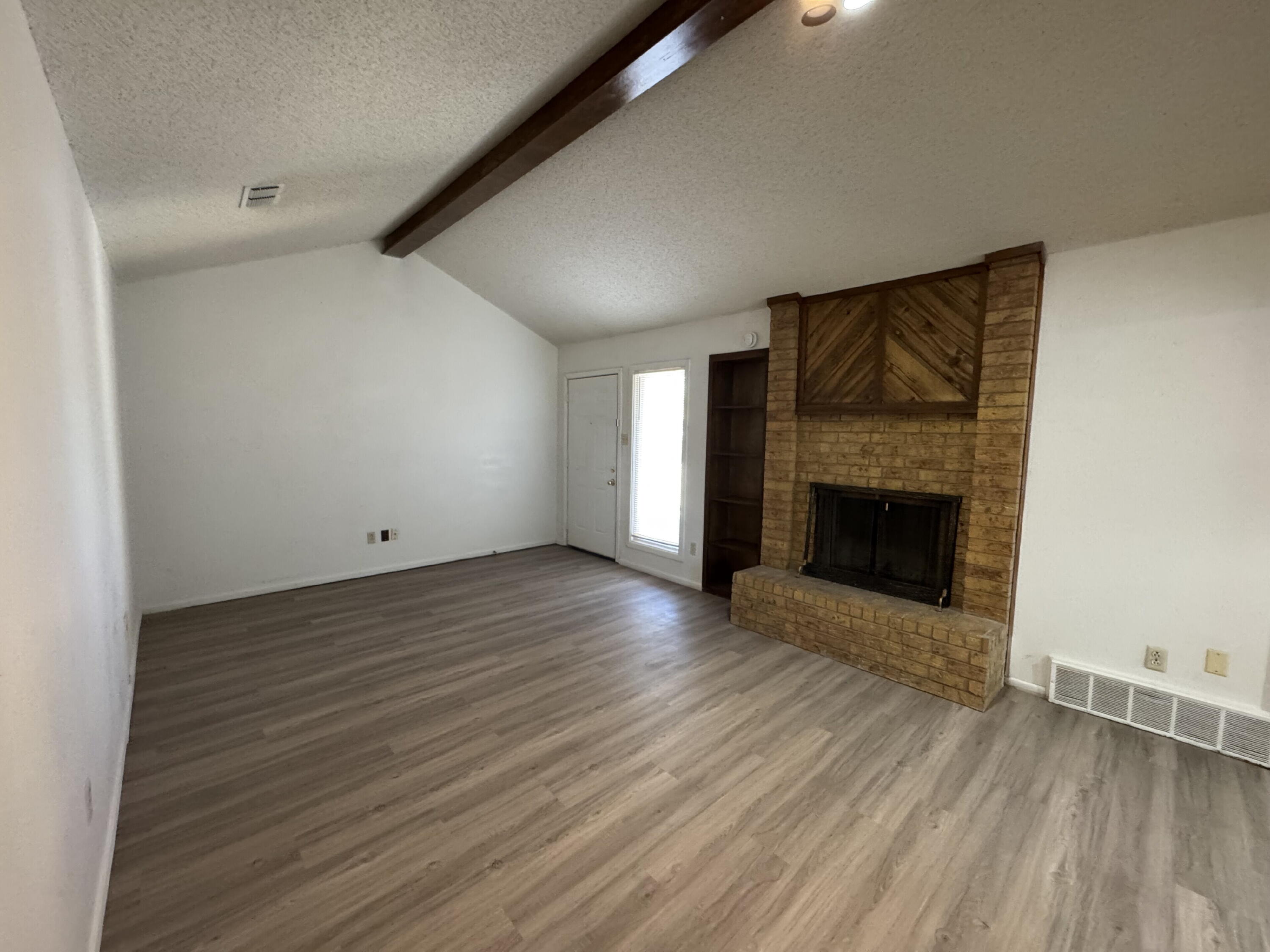 7403 Utica Avenue, Unit B Lubbock, TX 79424 - Photo 2 of 9 an empty room with wooden floor and fireplace