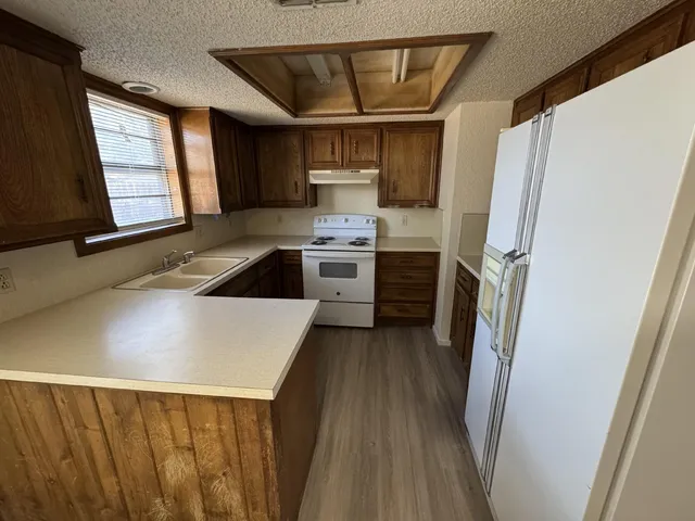 a kitchen with stainless steel appliances a stove a refrigerator a sink and dishwasher with wooden floor