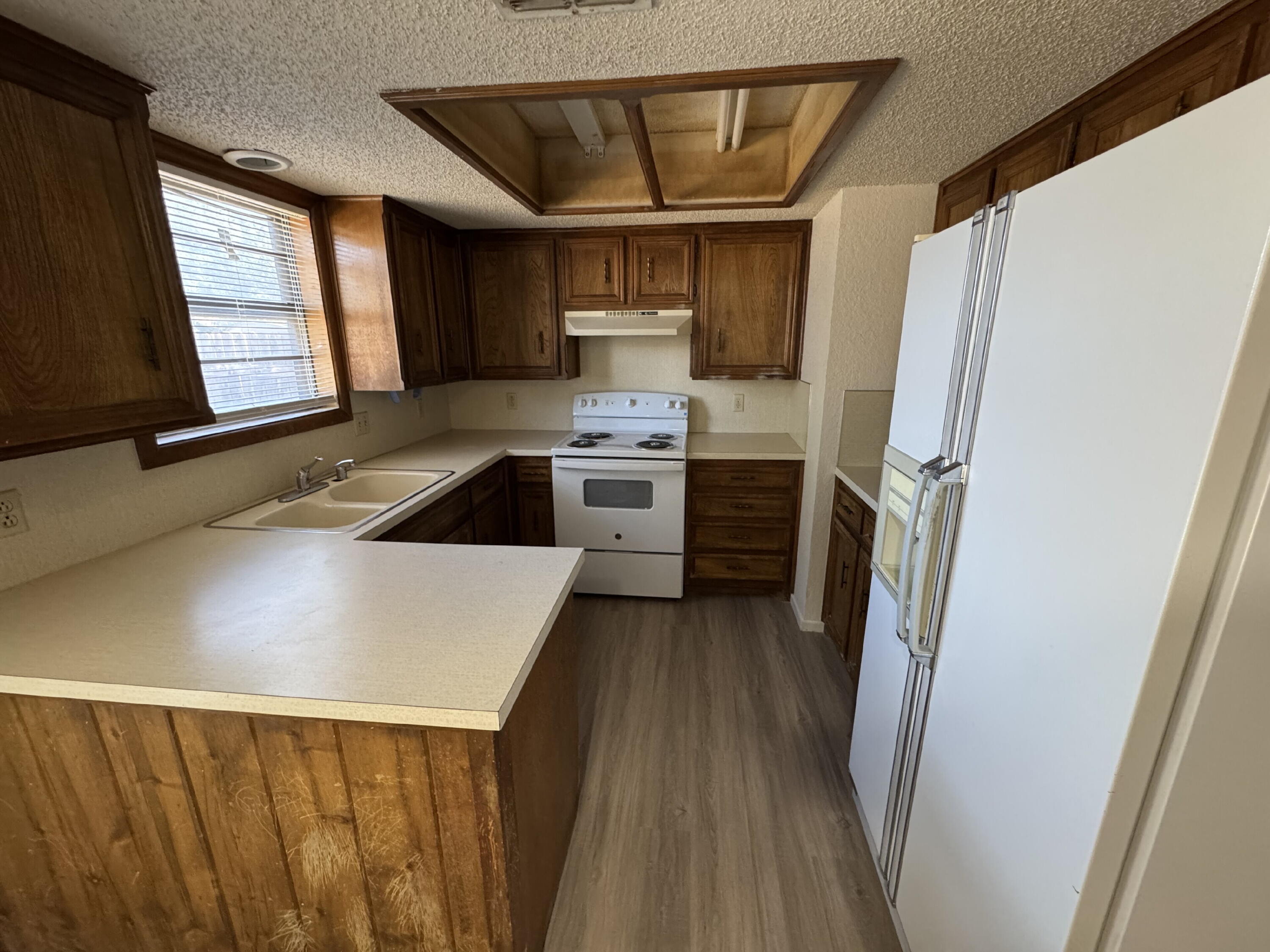 7403 Utica Avenue, Unit B Lubbock, TX 79424 - Photo 4 of 9 a kitchen with stainless steel appliances a stove a refrigerator a sink and dishwasher with wooden floor
