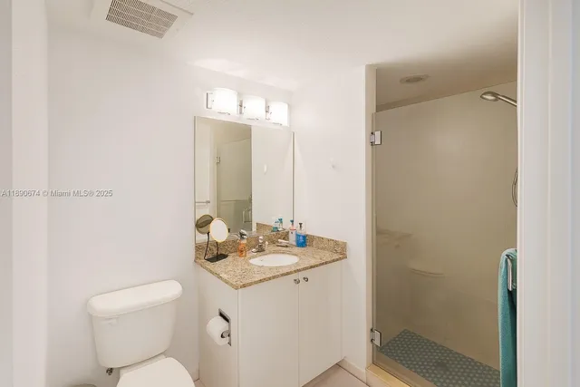 a bathroom with a granite countertop sink toilet a mirror and shower