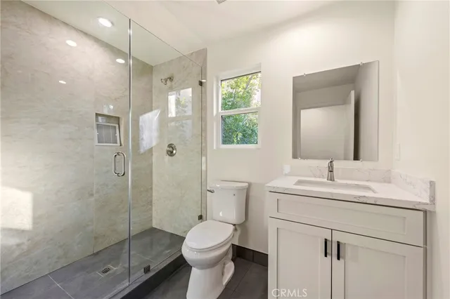 a bathroom with a shower sink vanity mirror and toilet