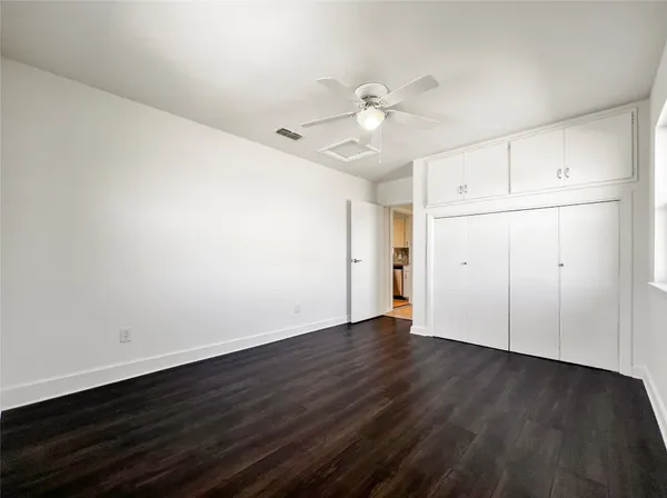 an empty room with wooden floor and fan