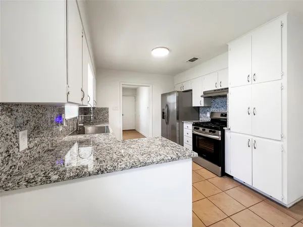 a kitchen with granite countertop a sink stove and refrigerator