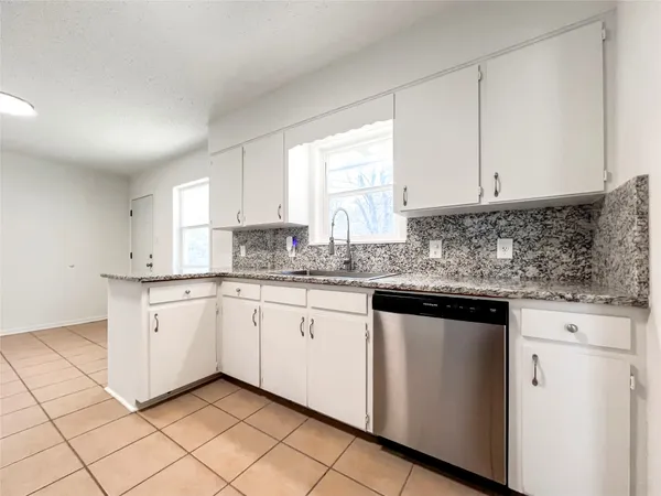 a kitchen with granite countertop white cabinets white appliances with a sink and dishwasher