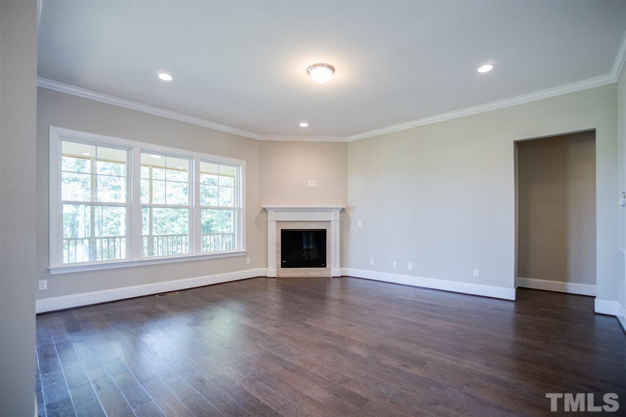 520 Adkins Ridge Road Rolesville, NC 27571 - Photo 4 of 25 an empty room with wooden floor fireplace and windows