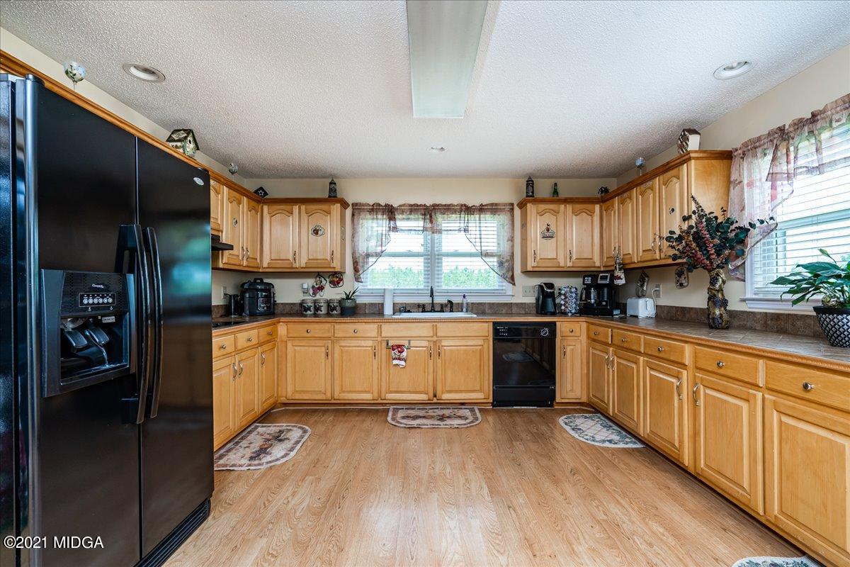 2696 Lower Hartley Bridge Road Byron, GA 31008 - Photo 20 of 24 a kitchen with stainless steel appliances granite countertop a refrigerator a sink dishwasher a stove and white countertops with wooden floor