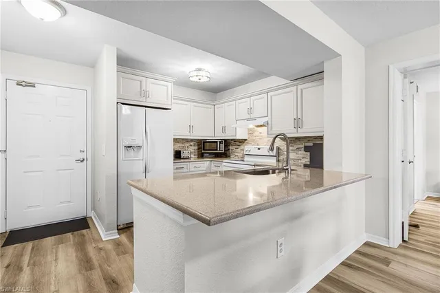 a large kitchen with a refrigerator a sink and cabinets
