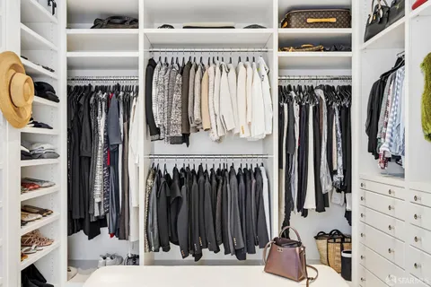 a view of walk in closet with clothes and shoes