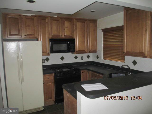 12704 Flack Street Silver Spring, MD 20906 - Photo 4 of 14 a kitchen with granite countertop a sink and a stove top oven with wooden floor
