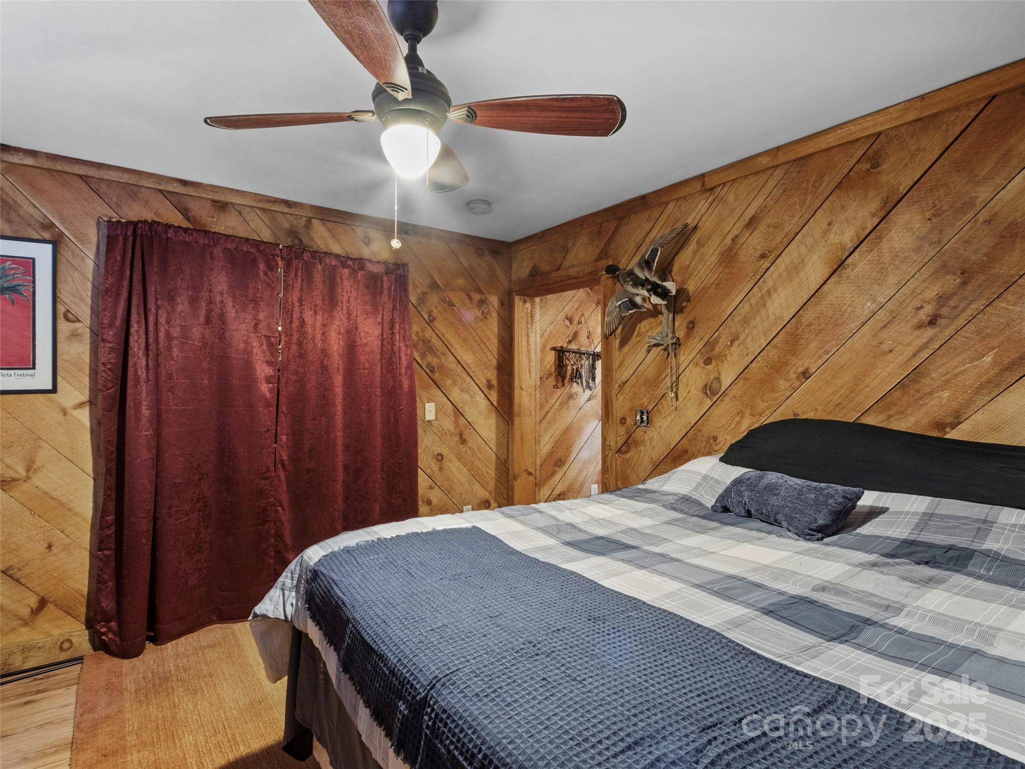 1571 Roaring Fork Road Burnsville, NC 28714 - Photo 28 of 37 a bedroom with a bed and a chandelier