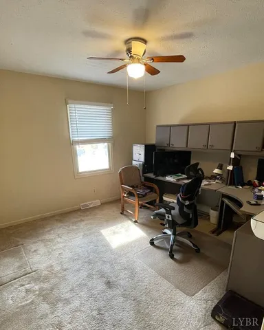 a view of a workspace with furniture and a window